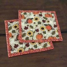 two placemats with pumpkins and sunflowers on them sitting on a table