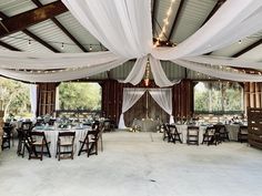 an indoor wedding venue with white draping and tables