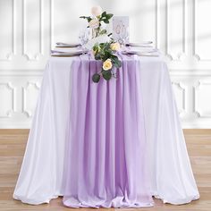 the table is set with purple and white linens