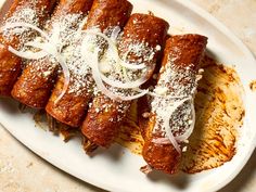 a white plate topped with food covered in sauce and onions on top of breaded pastries