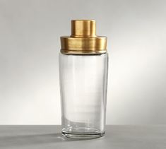 a clear glass jar with a gold lid on a table top, against a white background