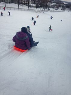 people are sledding down a hill in the snow