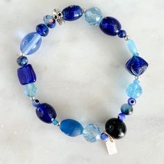 Blue crystal and sustainable bead bracelet. Silver skull charm. Sterling silver BelleStyle logo tag. Features lapis lazuli, Vintage Swarovski, Turkish Beads. Measures 7-8”. Unisex. Handmade in USA. Logo Tag, Blue Bracelet, Bracelet Silver, Blue Crystals, Bead Bracelet, Lapis Lazuli, Charm Bracelet, Beaded Bracelets, Bracelet