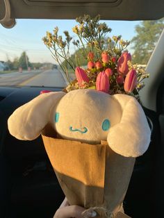 a stuffed animal holding flowers in the back of a car