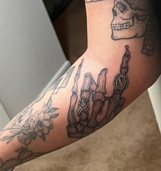 a person's arm with tattoos on it and a skull in the background,