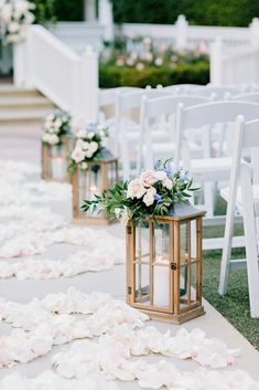 the aisle is lined with white petals and gold lanterns, which are filled with flowers