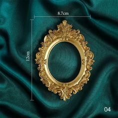 a gold frame sitting on top of a green satin covered tablecloth with measurements for it