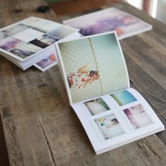 an open photo album sitting on top of a wooden table next to other photos and papers