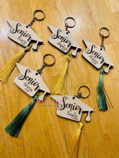 four graduation keychains with tassels on them sitting on a wooden table