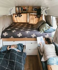 two children are reading books in the bed area of a small camper with bunk beds