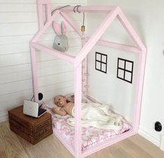 the baby is sleeping in her pink doll house bed, which has been made out of cardboard