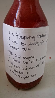 a jar of raspberry coulie on a white surface with a note attached to it