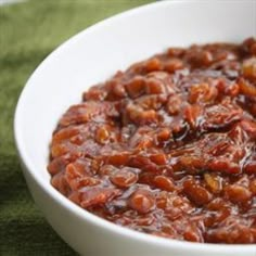 a white bowl filled with cooked beans on top of a green cloth