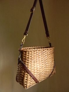 a woven purse hanging from a hook on a wall with a leather belt around it