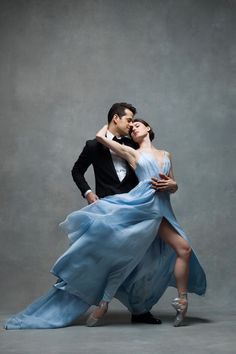 a man and woman are dancing together in blue dress with one leg on the other