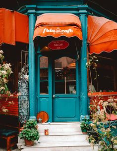 an orange and blue awning over the entrance to a restaurant with potted plants