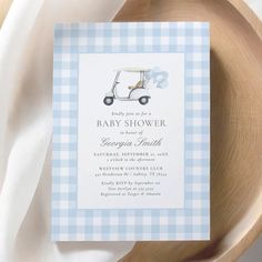 a blue and white checkered baby shower with a golf cart in the background on a wooden plate