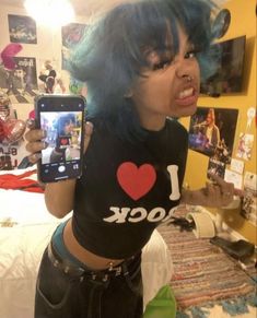 a woman with blue hair is holding up her cell phone and taking a selfie