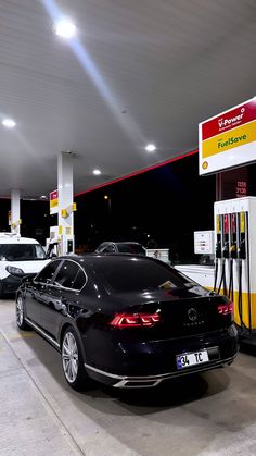 two cars at a gas station, one is black and the other has white trim