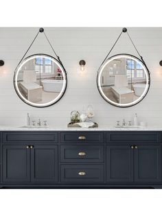 two round mirrors hanging on the side of a wall above a double sink and mirror