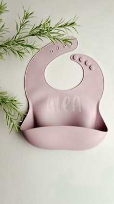 a pink bib with the word aisa written on it next to a green branch