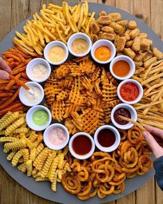 a platter filled with lots of different types of fries and dipping sauces on top of it