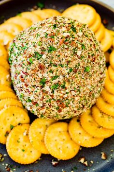 a plate with crackers and a cheese ball on the top, surrounded by small crackers