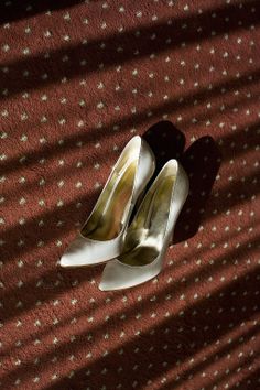 a pair of white high heel shoes sitting on top of a red carpeted floor