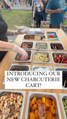 people standing around a table with trays of food on it and the words, announcing our new charcuterie cart