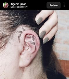 a woman has her ear pierced with an arrow tattoo