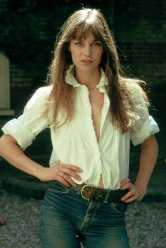 a woman with long hair wearing jeans and a white shirt is posing for the camera