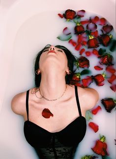 a woman laying in a bathtub with rose petals around her neck and eyes closed