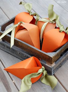 two orange paper hearts in a wooden box with ribbon on the top and green bows tied around them