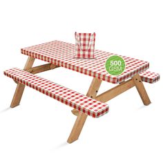 a picnic table with a red and white checkered cloth on it, sitting in front of a green sign that says 500 gmm