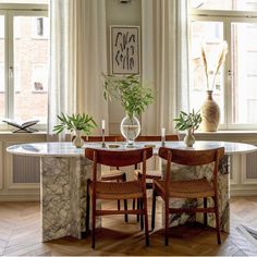 a dining room table with two chairs and a vase filled with flowers on top of it