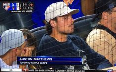 a baseball player sitting in the dugout with other players behind him looking at something