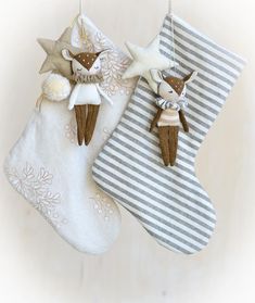 two christmas stockings hanging from the ceiling with decorations on them and one is holding an angel ornament