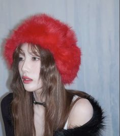 a woman with long hair wearing a red hat and black fur stole around her neck