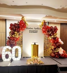 the balloon arch is decorated with red, gold and white balloons that spell out the number 60