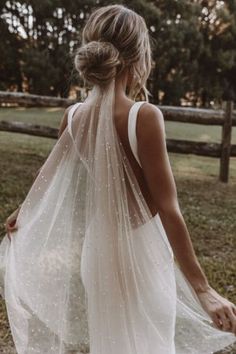 the back of a woman wearing a white wedding dress with sheer, beaded detailing