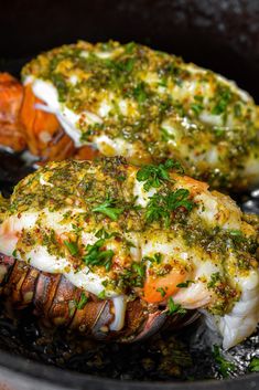 two cooked lobsters with herbs and seasoning in a skillet