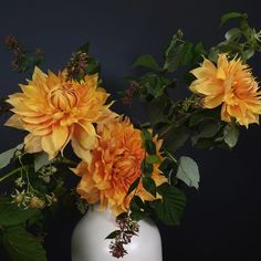 a white vase filled with yellow flowers on top of a table