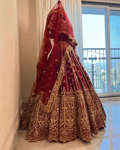 a woman in a red and gold bridal gown standing next to a white wall