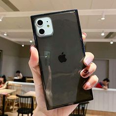 a person holding up an iphone case in a room with people sitting at tables and eating