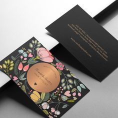 two black and gold business cards with flowers on them