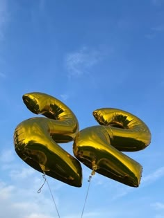 gold foil balloons floating in the air on a clear day with blue sky behind them