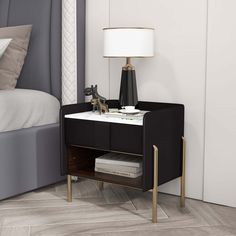 a nightstand with a lamp on top of it next to a bed