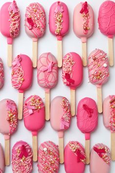 there are many pink lollipops with sprinkles and bows on them