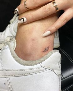 a woman's foot with two rings on it and a small tattoo on her left ankle