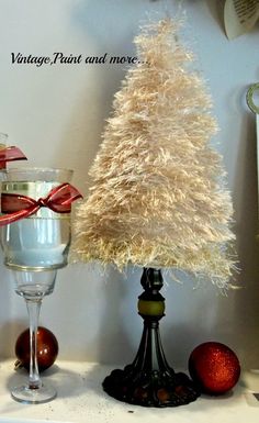 a small christmas tree sitting on top of a table next to two glasses filled with liquid